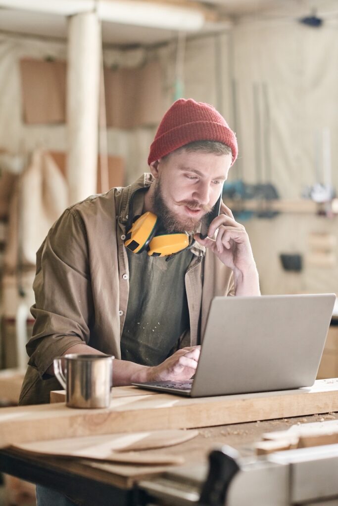 Tischler mit Laptop in der Werkstatt – Social Media Marketing für Handwerk